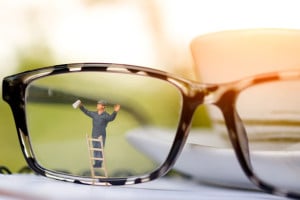 Miniature people worker cleaning eyes glasses.