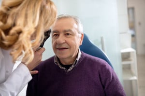 Senior looks in instrument for checking eyes at ophthalmologist