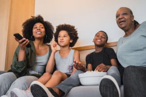 Grandmother, mother and children watching a movie at home.