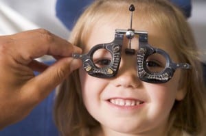 3485598 - optometrist in exam room with young girl in chair smiling