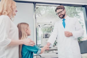 Small cute blond female patient is greeting the friendly bearded